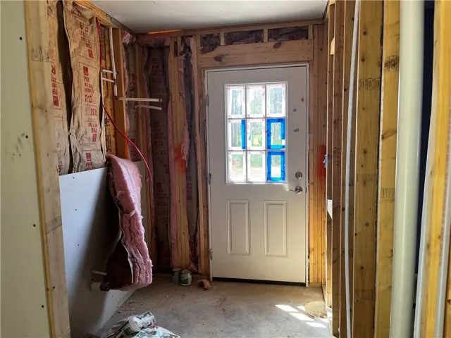 Unfinished framing reveals insulation and an exterior door, hinting at future living spaces.