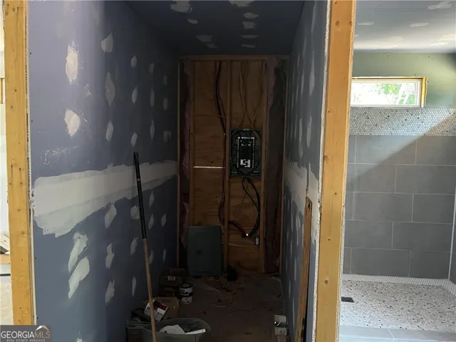 A glimpse into construction, with a partially finished electrical panel area and a tiled shower awaiting completion.