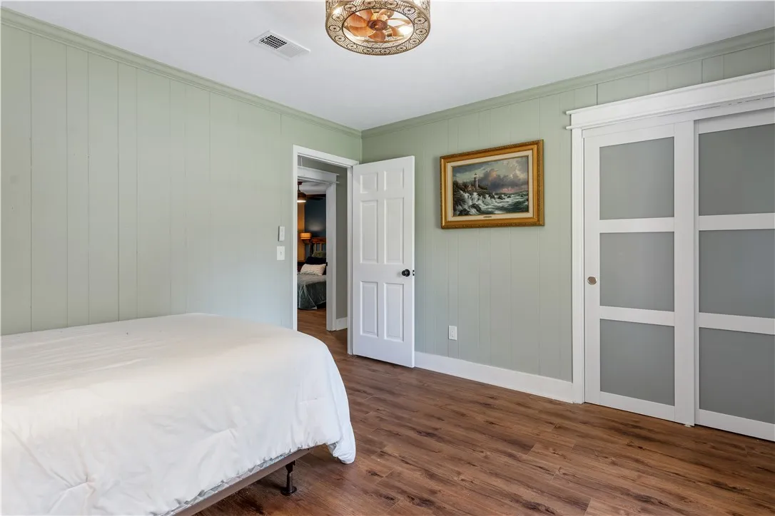 Rich hardwood-style flooring and paneled walls create a cozy atmosphere in this restful bedroom.