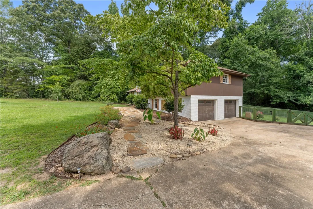 Drive into an inviting home with a natural landscape and dual garage doors.