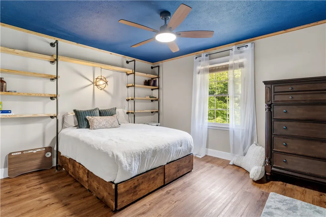 A comforting bedroom features built-in shelving, durable flooring, and a window with abundant natural light.