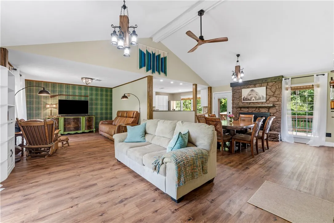 A spacious living area combines comfort and functionality with a striking stone fireplace and durable wood flooring.