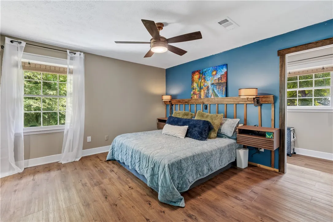 Laminate flooring and a functional ceiling fan offer comfort in this peaceful sleeping area.