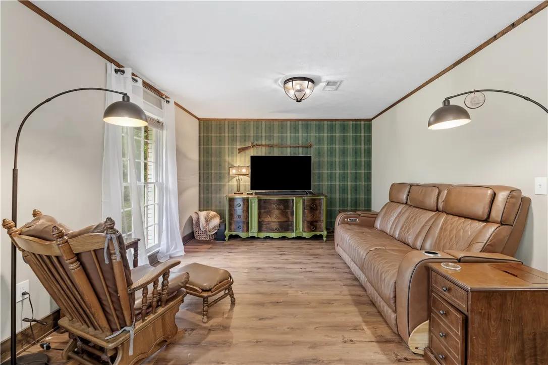 Hardwood-style flooring extends across this well-lit living area, featuring a unique accent wall.