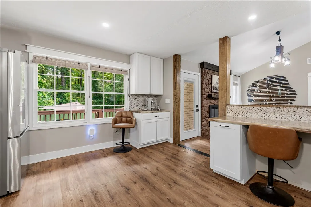 Well-lit kitchen with rich wood flooring and a view to the deck and lush greenery.