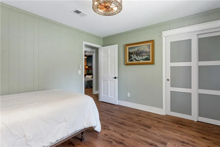 Rich hardwood-style flooring and paneled walls create a cozy atmosphere in this restful bedroom.