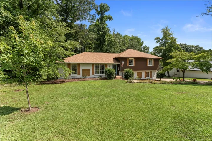A classic facade with contrasting colors provides a welcoming presence set against a lush, green landscape.