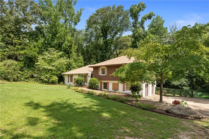 A classic home, perfectly nestled amongst flourishing greenery, offers a generous front yard and inviting curb appeal.