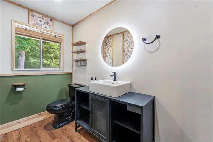 A well-appointed bathroom features wood-look flooring and a unique vanity with a vessel sink.