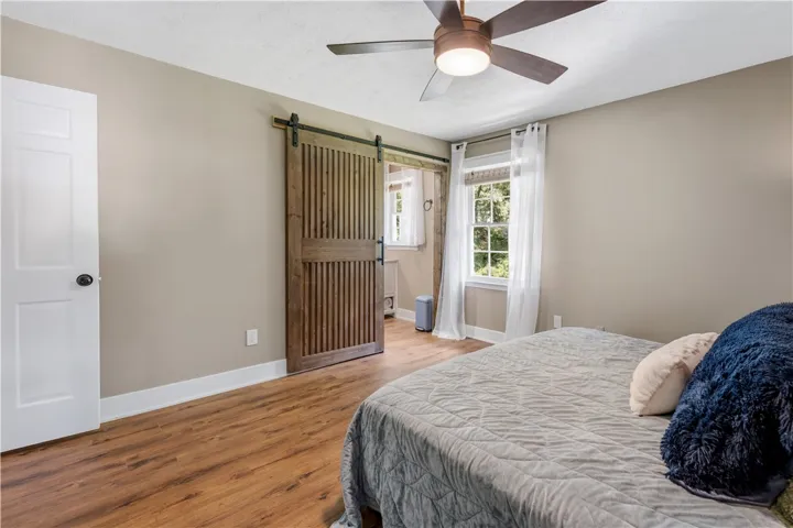 A comfortable bedroom with a barn door and wood flooring invites relaxation.