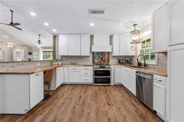 Bright, open kitchen with abundant cabinetry and warm wood flooring creates an inviting atmosphere.