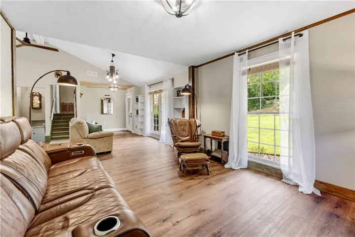Natural light floods this inviting living area, highlighting its gleaming hardwood flooring.