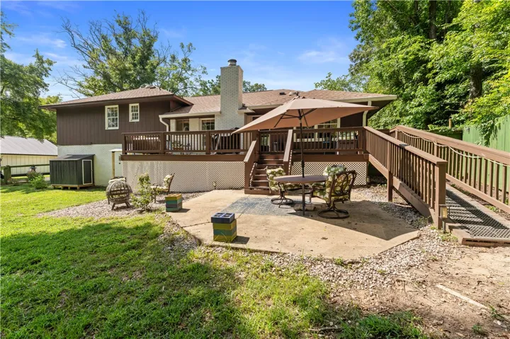 An inviting elevated deck extends to a paved patio, offering ample space for outdoor relaxation and entertaining.