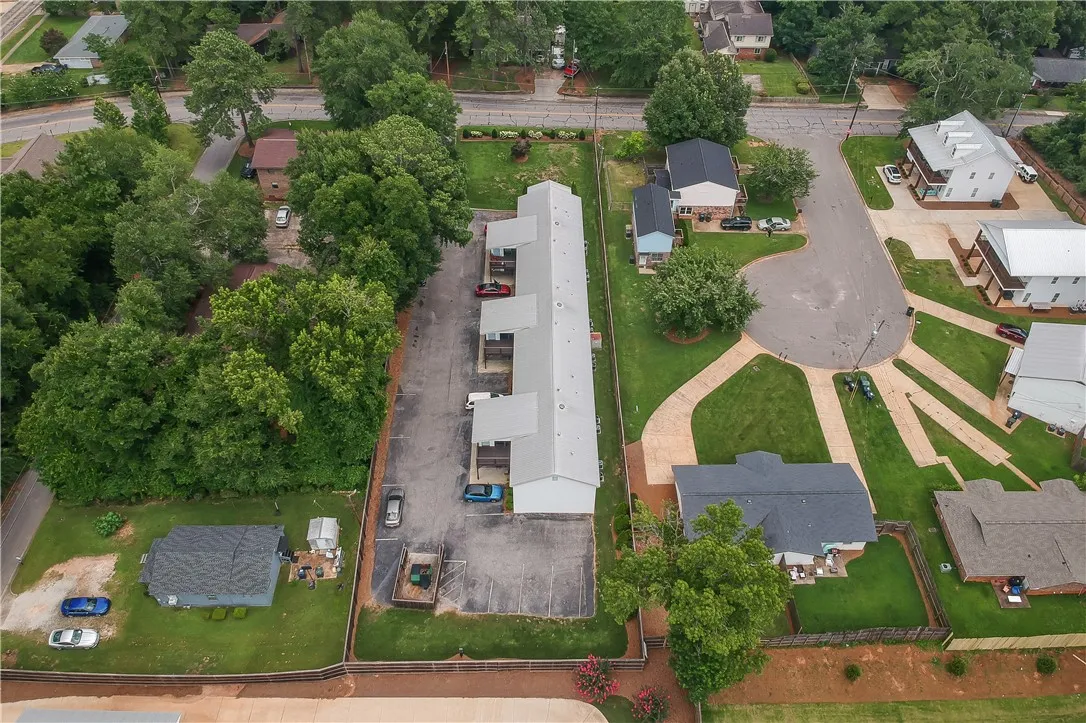 An aerial perspective reveals a comprehensive view of the property with a long structure, parking areas, and surrounding neighborhood.
