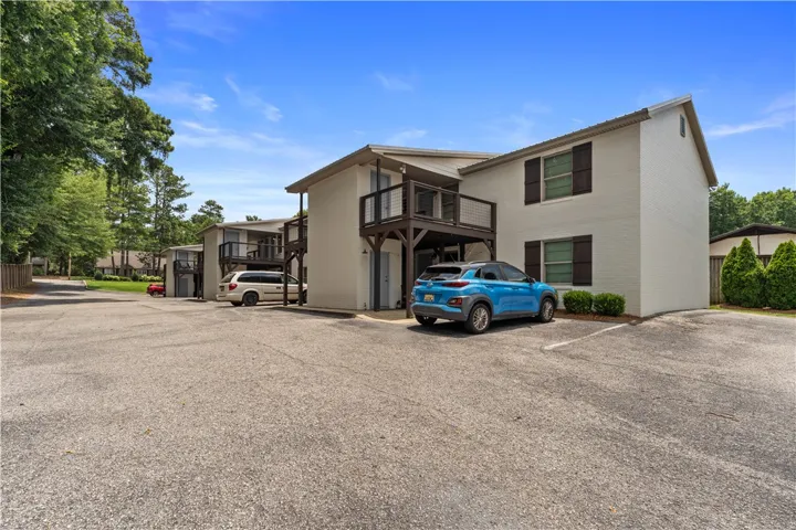 Multi-story complex with a paved parking area and mature landscaping.