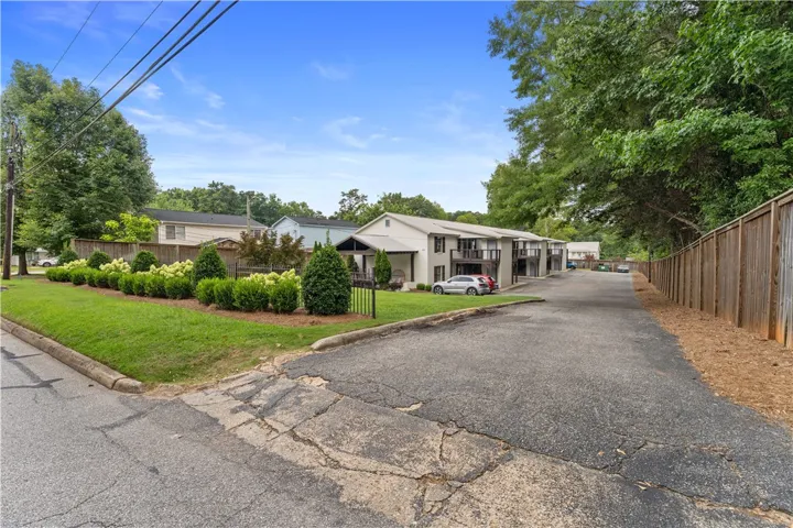 A quiet residential street showcases an inviting apartment complex with established landscaping and convenient parking.