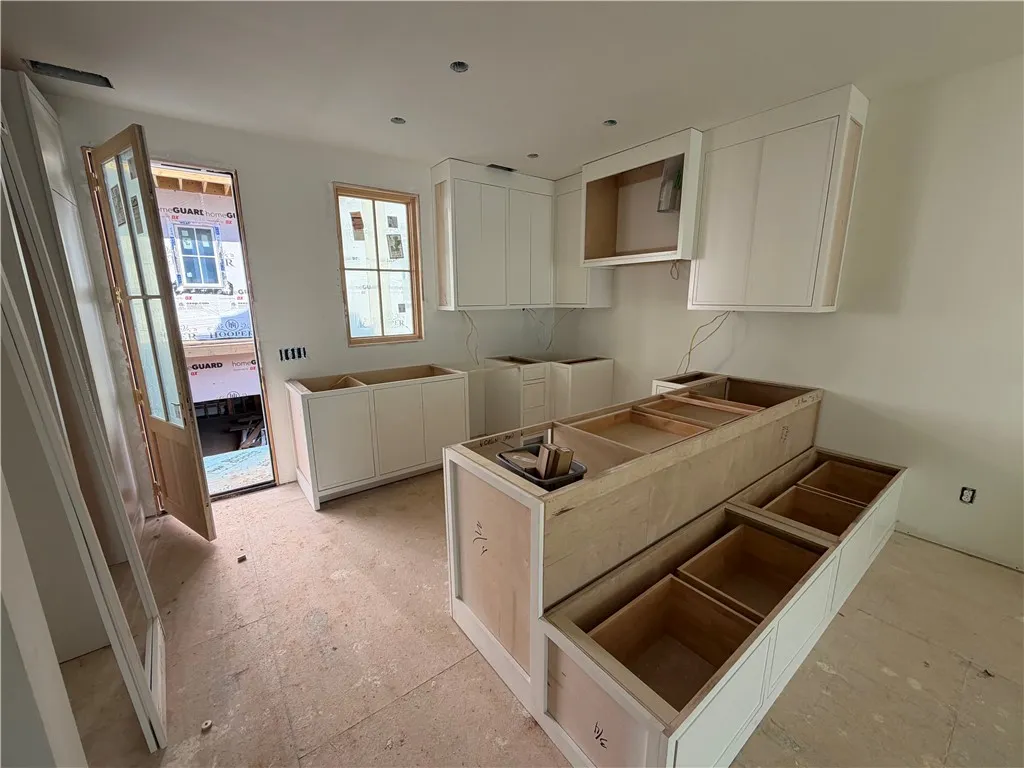A well-lit kitchen space awaits custom finishes, featuring new cabinetry and an open layout.