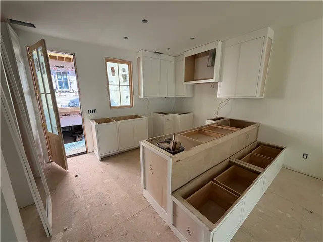 A well-lit kitchen space awaits custom finishes, featuring new cabinetry and an open layout.