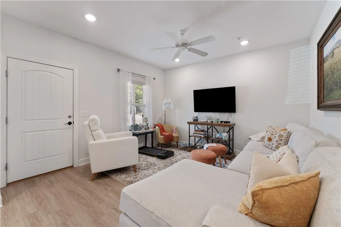 A comfortable living area with light wood flooring and bright recessed lighting.