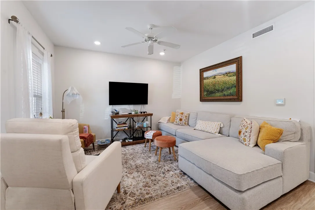 A naturally illuminated living room showcasing elegant recessed lighting and light wood flooring.