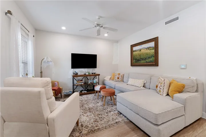 A naturally illuminated living room showcasing elegant recessed lighting and light wood flooring.
