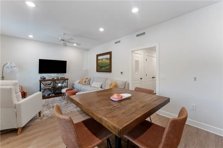 Recessed lighting and a ceiling fan illuminate this inviting living area with a dining space.