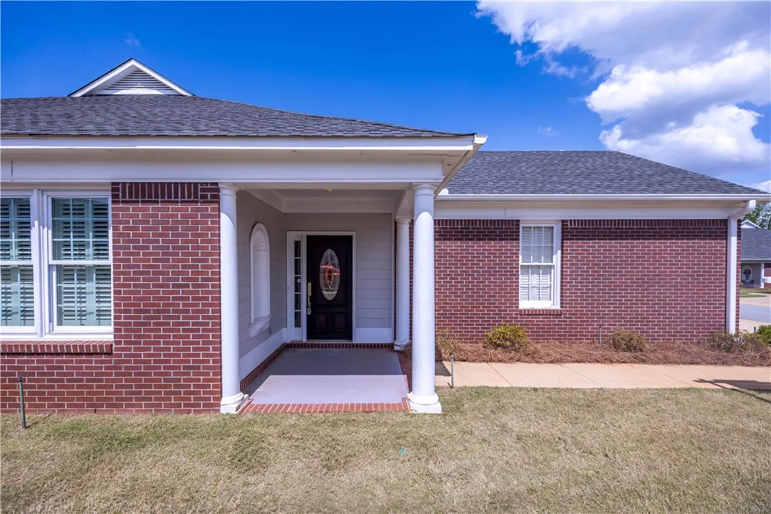 A classic brick exterior presents a welcoming entryway with stately columns and a decorative front door.