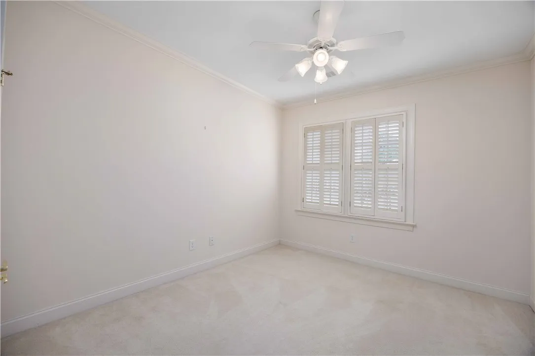A quiet bedroom with a ceiling fan offers peaceful repose and ample natural light.