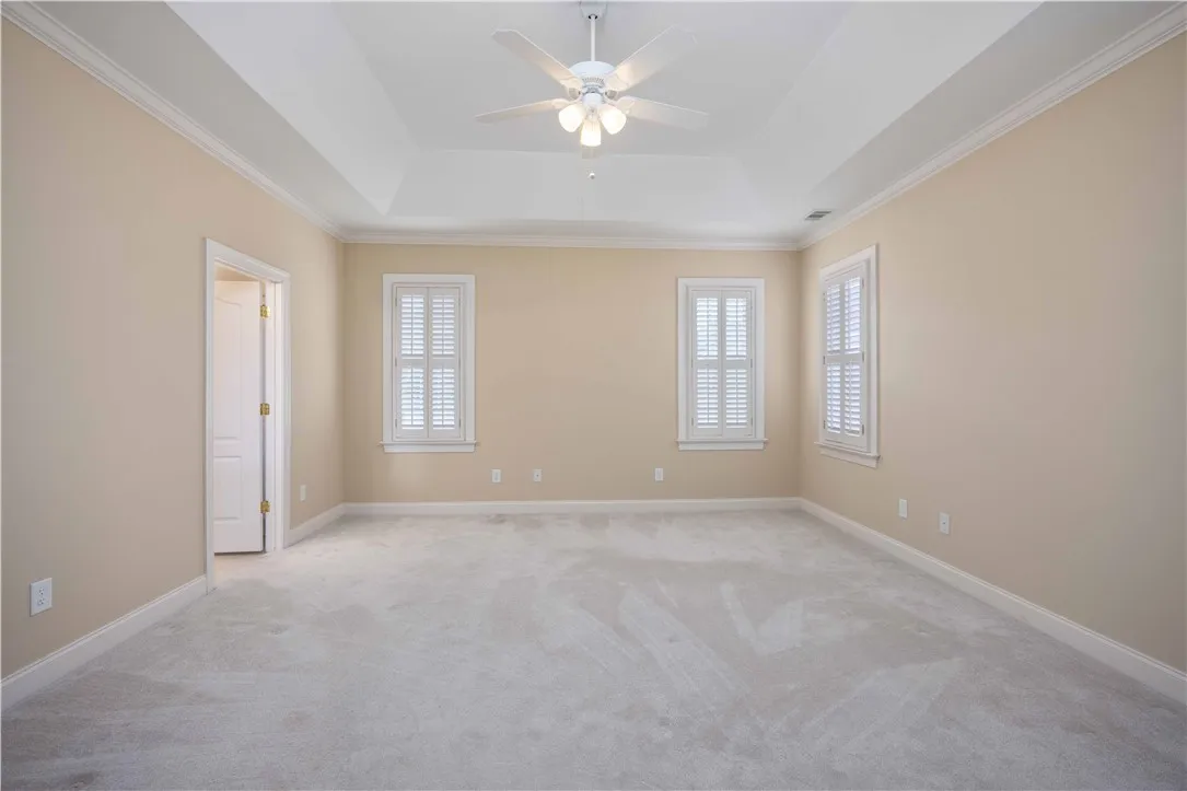 A spacious bedroom offers comfort with soft carpeting and elegant plantation shutters.