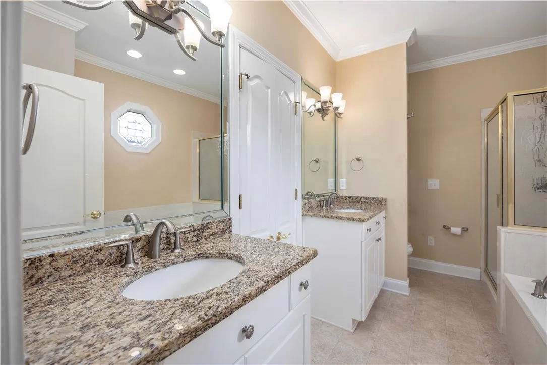 Dual vanities with granite counters define this generously appointed primary bathroom.