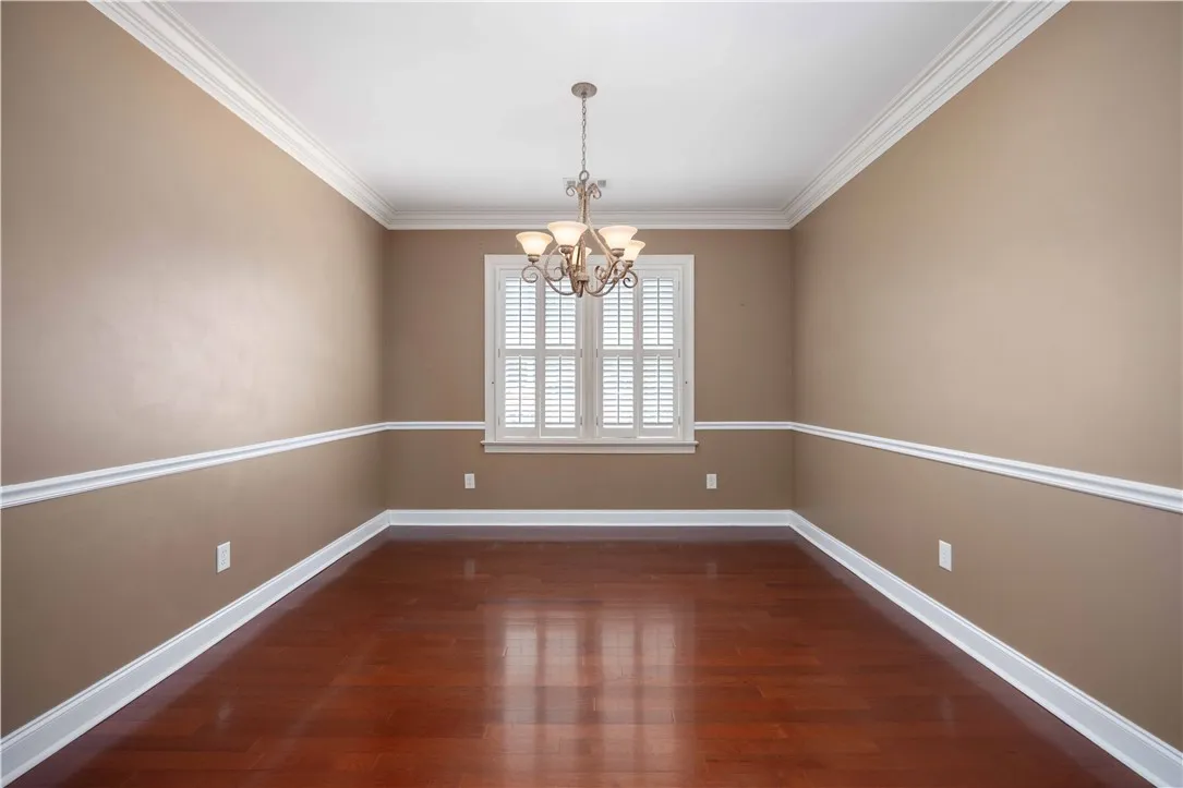 Hardwood flooring complements classic crown molding and wainscoting in this inviting space.