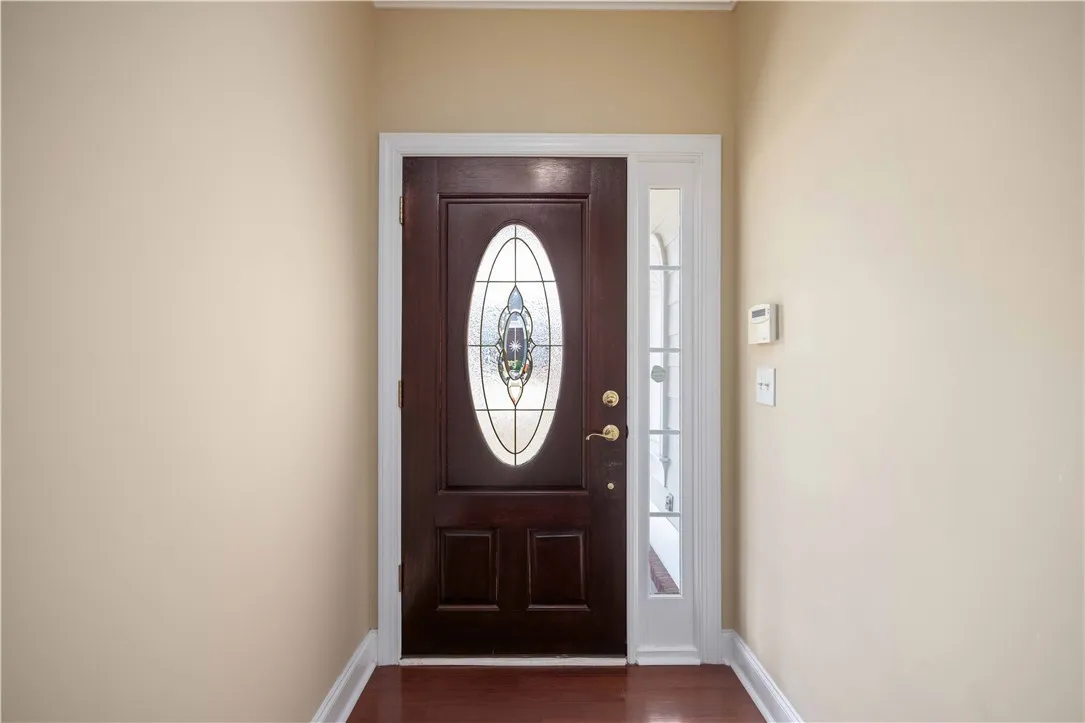 Enter into a bright hallway featuring rich hardwood floors and a distinguished stained glass door.
