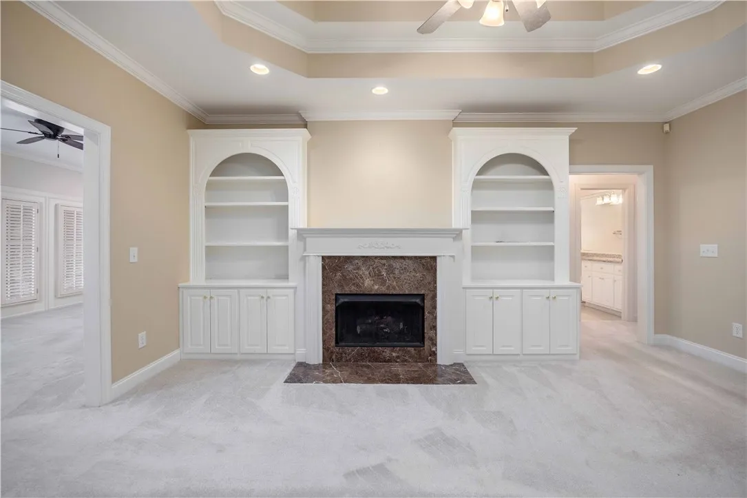Built-in shelving flanks a grand fireplace, creating an elegant focal point in this inviting living space.
