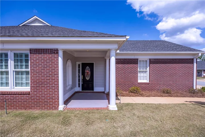 A classic brick exterior presents a welcoming entryway with stately columns and a decorative front door.