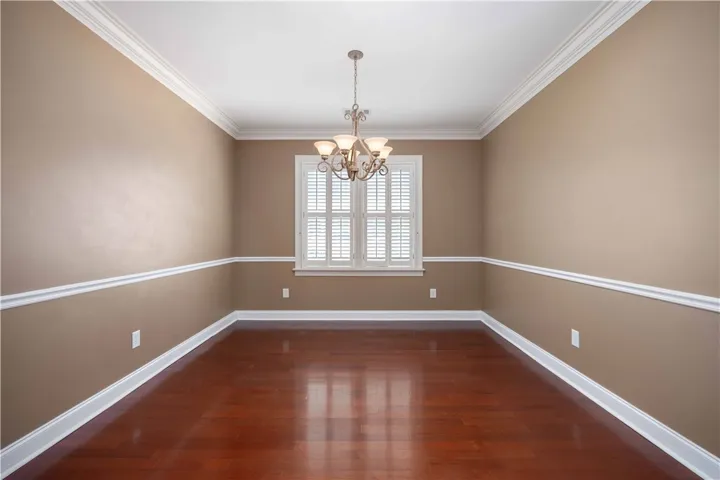 Hardwood flooring complements classic crown molding and wainscoting in this inviting space.