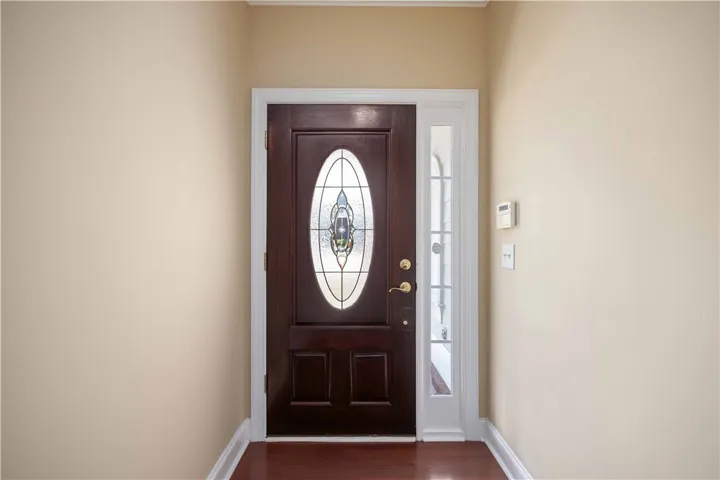 Enter into a bright hallway featuring rich hardwood floors and a distinguished stained glass door.
