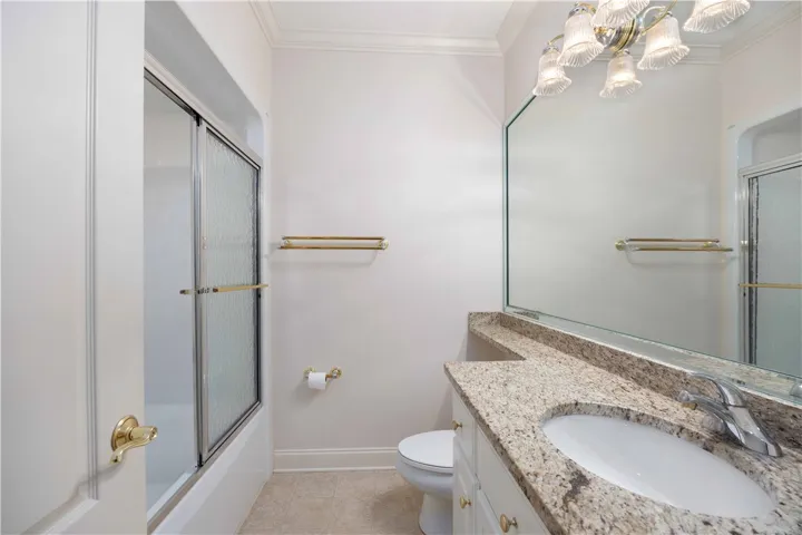 A well-appointed bathroom features a single vanity with a granite countertop and a shower-tub combination with a sliding glass door.