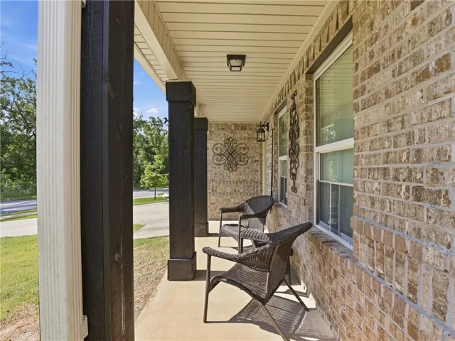 A welcoming front porch features sturdy dark pillars and a classic brick exterior, offering an inviting entry.