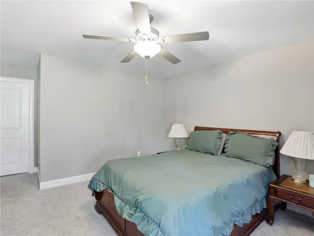 Comfortable bedroom retreat features soft gray walls and a ceiling fan for year-round climate control.