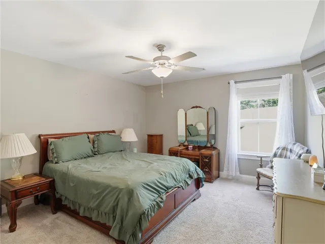 A tranquil bedroom features plush carpet and a well-lit window, perfect for serene mornings.