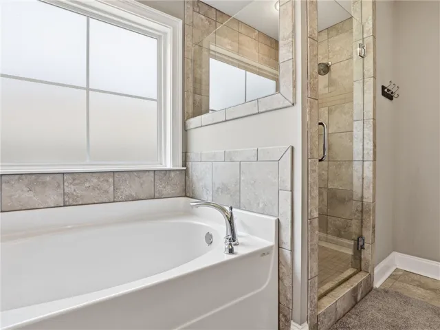 Indulge in a tranquil bathing experience with this spacious soaking tub and adjacent glass-enclosed shower.