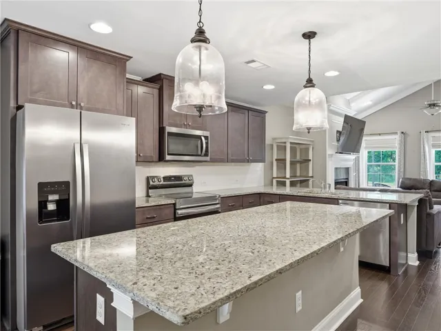 Granite countertops and rich wood cabinetry define this well-appointed kitchen, flowing seamlessly into the inviting living area.