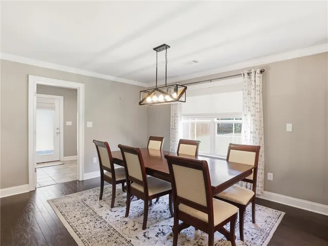 A refined dining space featuring hardwood floors and an elegant window overlooking the backyard.