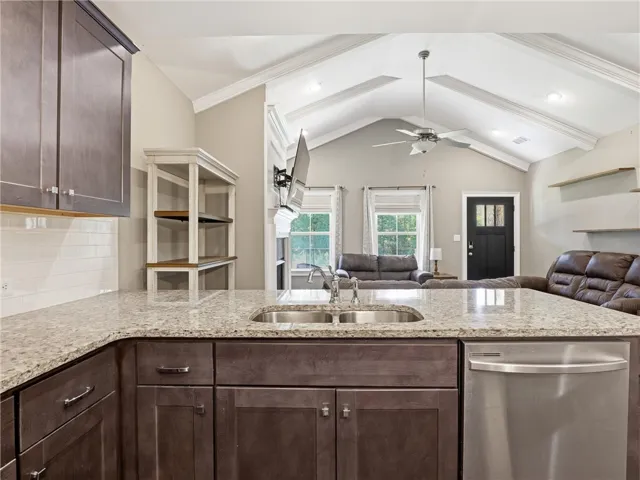 A chef's dream kitchen offers a double sink and ample granite counter space, seamlessly flowing into a spacious living area with vaulted ceilings.