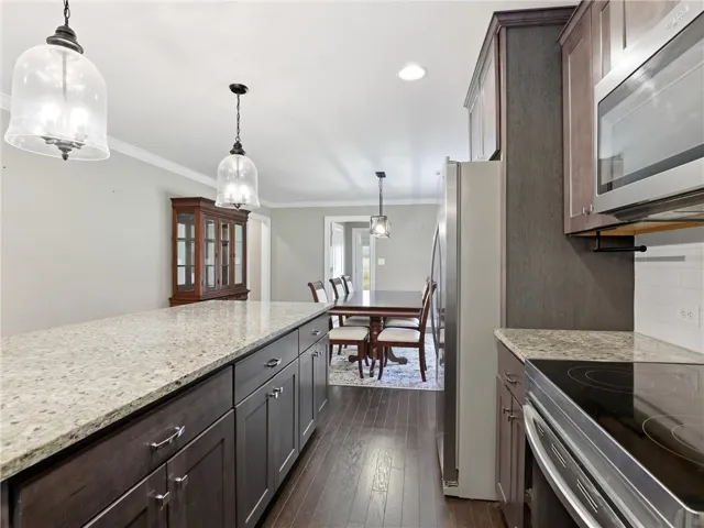 Granite counters and rich wood cabinetry create a functional, stylish kitchen flowing into a well-lit dining area.