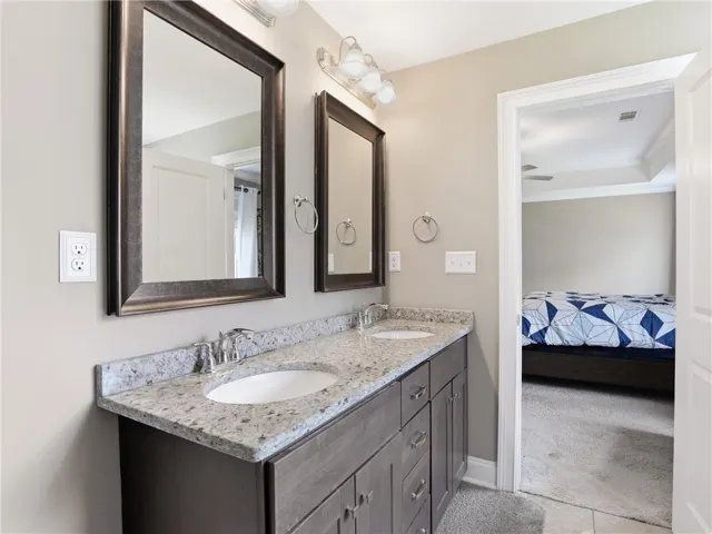 Double vanity with stone counters provides ample space and functionality in this well-appointed bathroom.