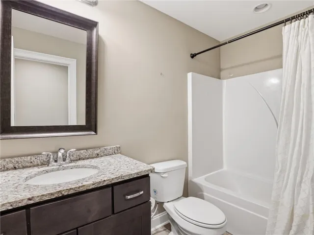 A compact full bath features a single vanity with granite counters and a white shower-over-tub.