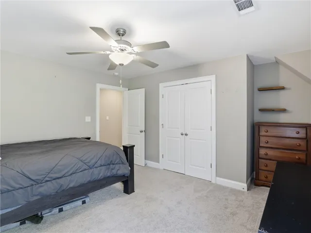 Restful bedroom retreat with soft carpeting and ceiling fan for optimal comfort.