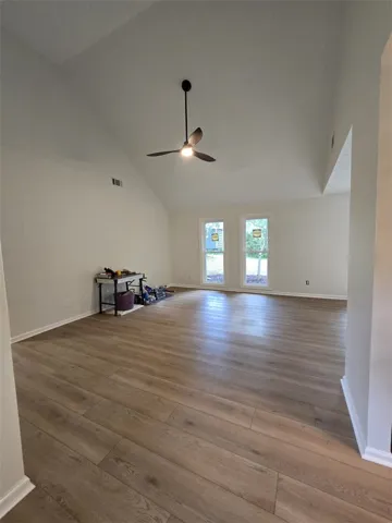 A voluminous living space features high vaulted ceilings and durable wood flooring.
