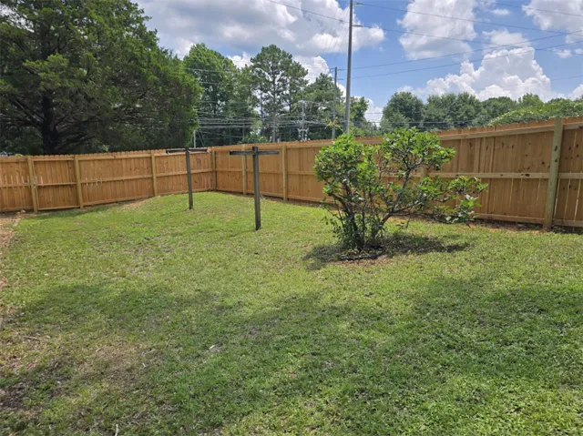 A verdant lawn, fully enclosed by a newly installed wooden fence, offers privacy and space for outdoor enjoyment.